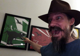 Jay wears a fedora and points at a painting of a dinosaur